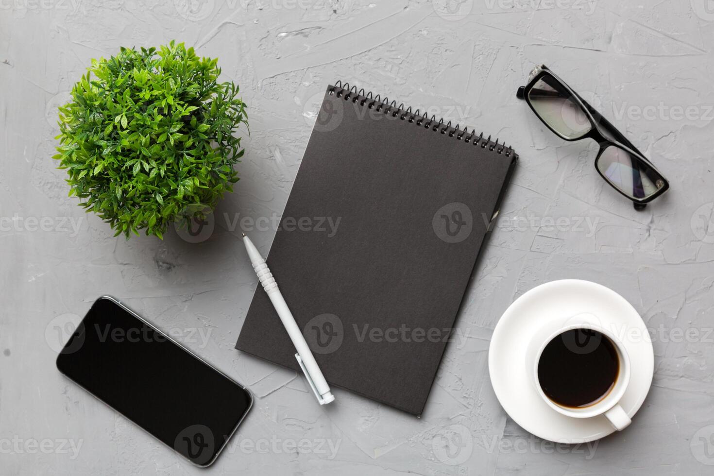 moderno ufficio scrivania tavolo con taccuino, smartphone e altro forniture con tazza di caffè. vuoto taccuino pagina per voi design. superiore Visualizza, piatto posare foto