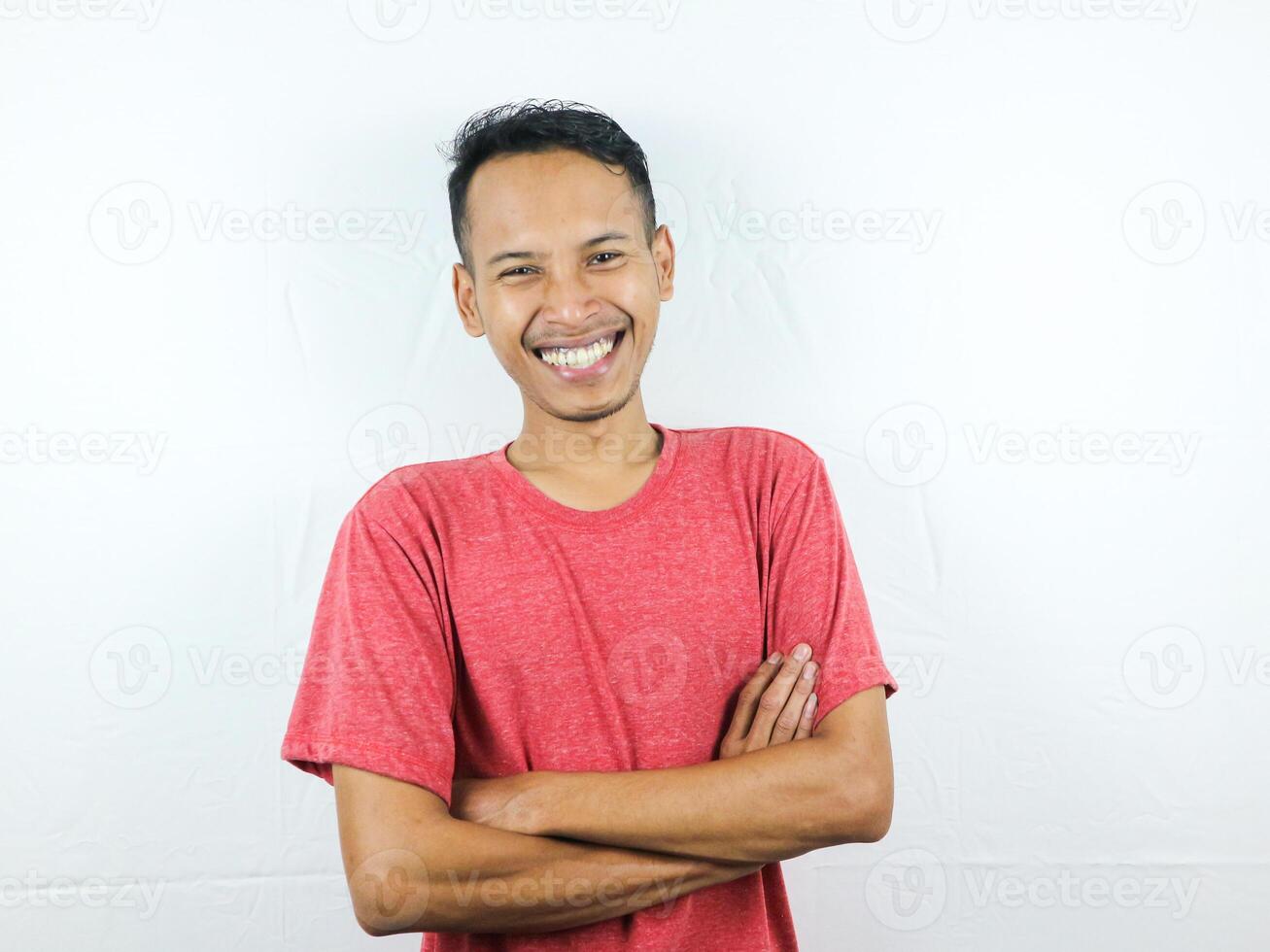 sorridente bello asiatico uomo nel casuale rosso maglietta con braccio attraversato foto