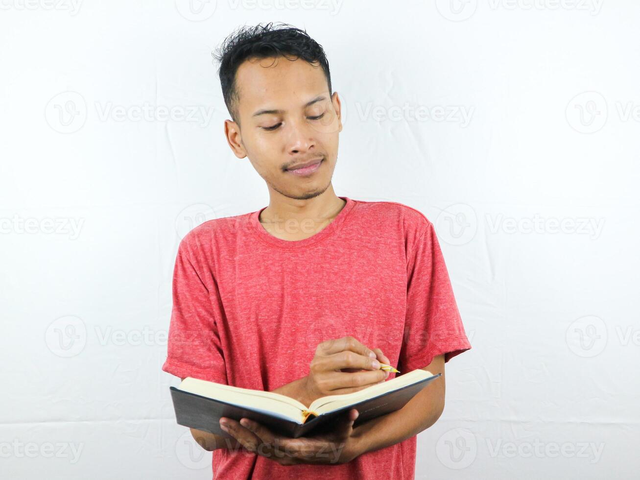 ritratto di un asiatico uomo Tenere penna e scrittura libro isolato su bianca sfondo. foto