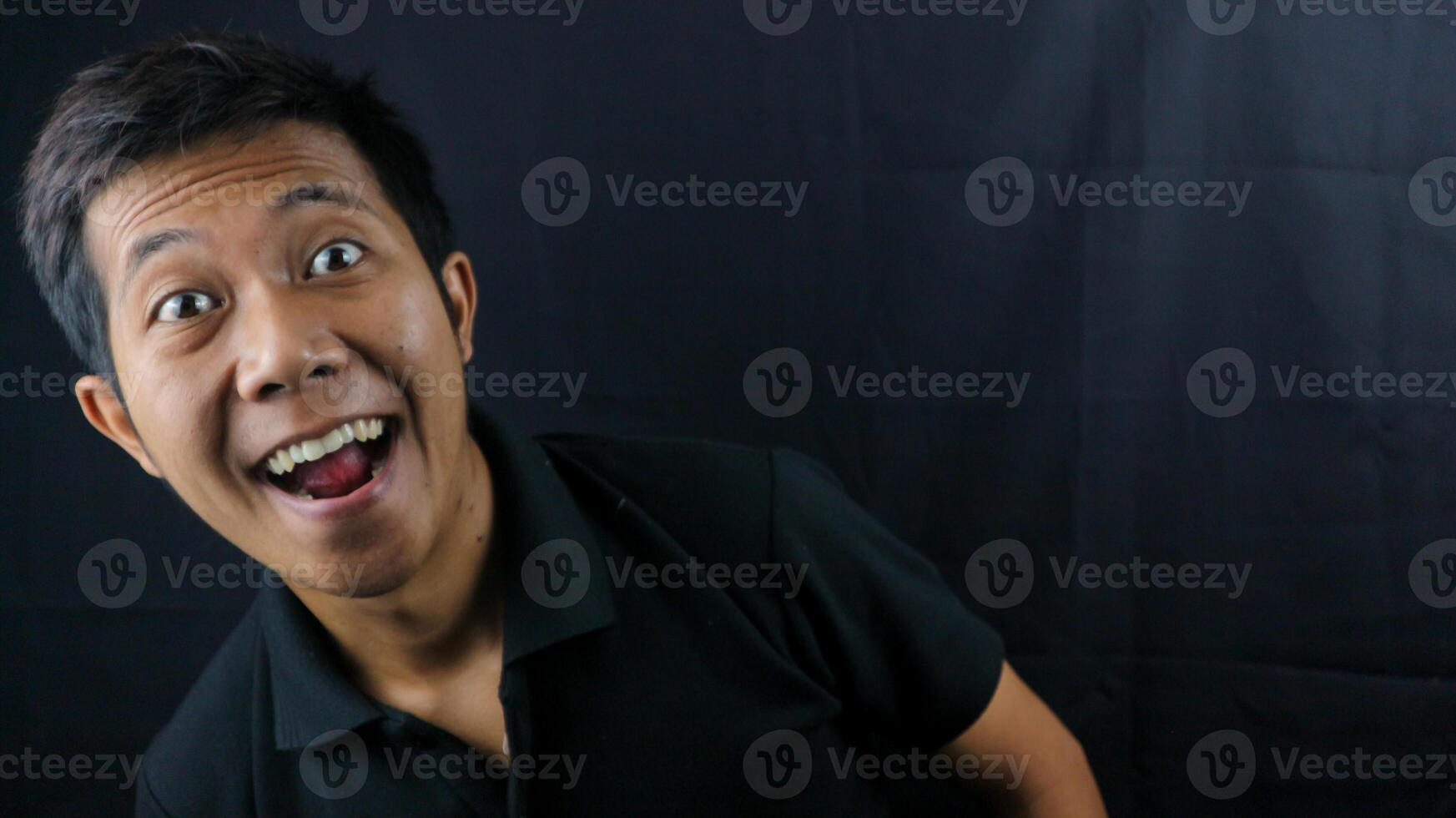 asiatico uomo con ridendo viso espressione su nero sfondo. foto