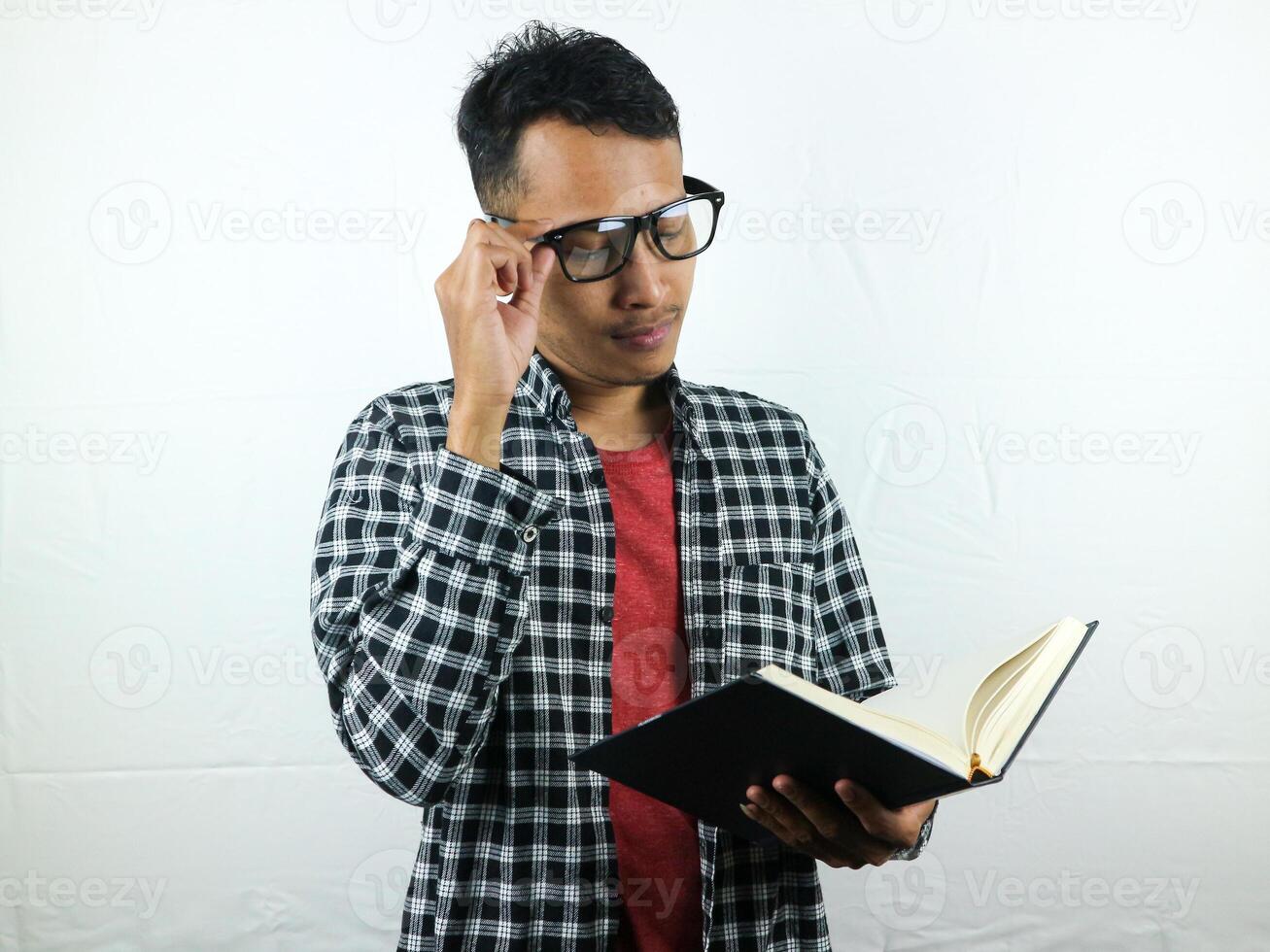 bello asiatico alunno sorridente e Tenere e lettura libro nel mano foto