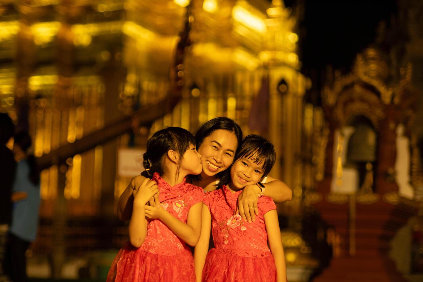 contento famiglia, madre e sua bambini posa per il telecamera a d'oro pagoda a wat Phra quello haripunchai woramahawihan nel lamphun, nord di Tailandia. foto