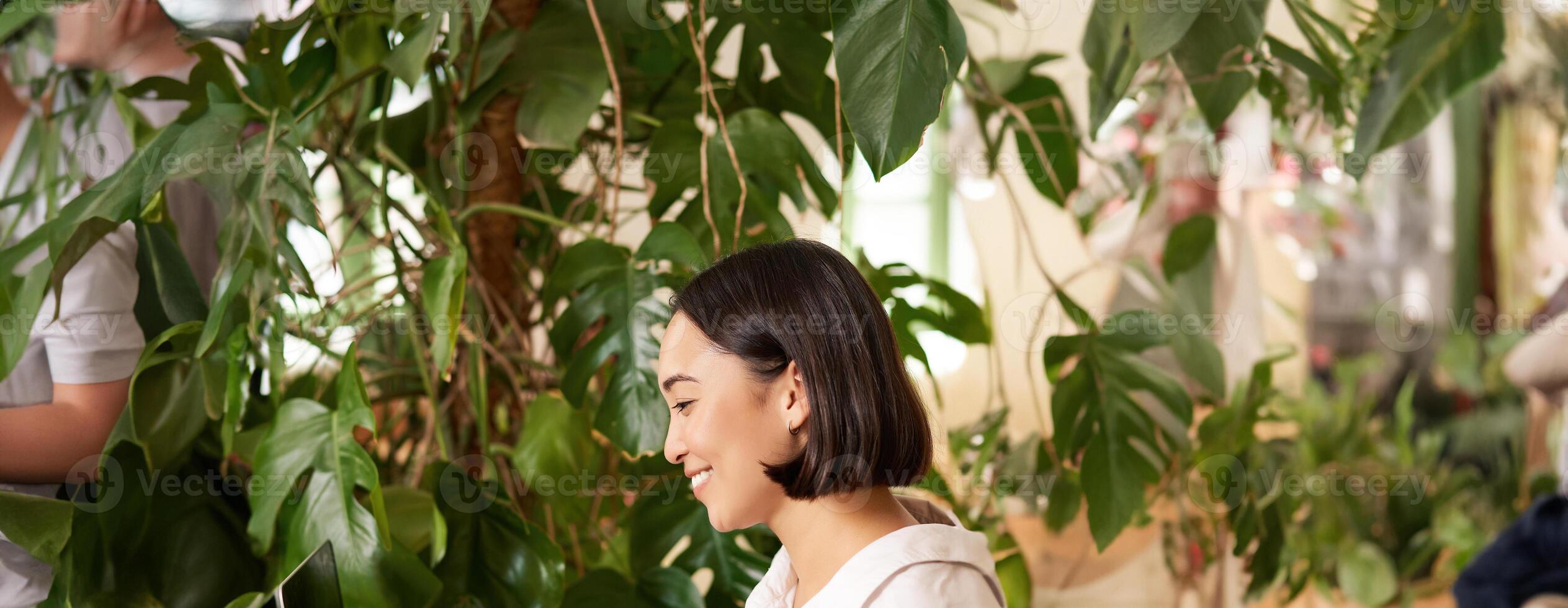 verticale tiro di bellissimo donna si siede nel bar con computer portatile, lavori o studi in linea a co-working spazio, sorridente rilassato foto