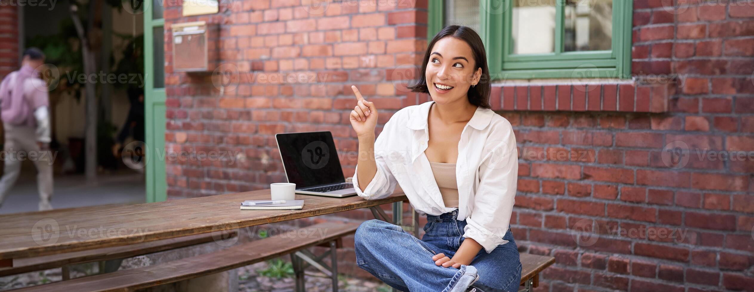 entusiasta asiatico donna, puntamento a superiore giusto angolo, mostrando annuncio, notizia su striscione, guardare impressionato e incuriosito di smth foto