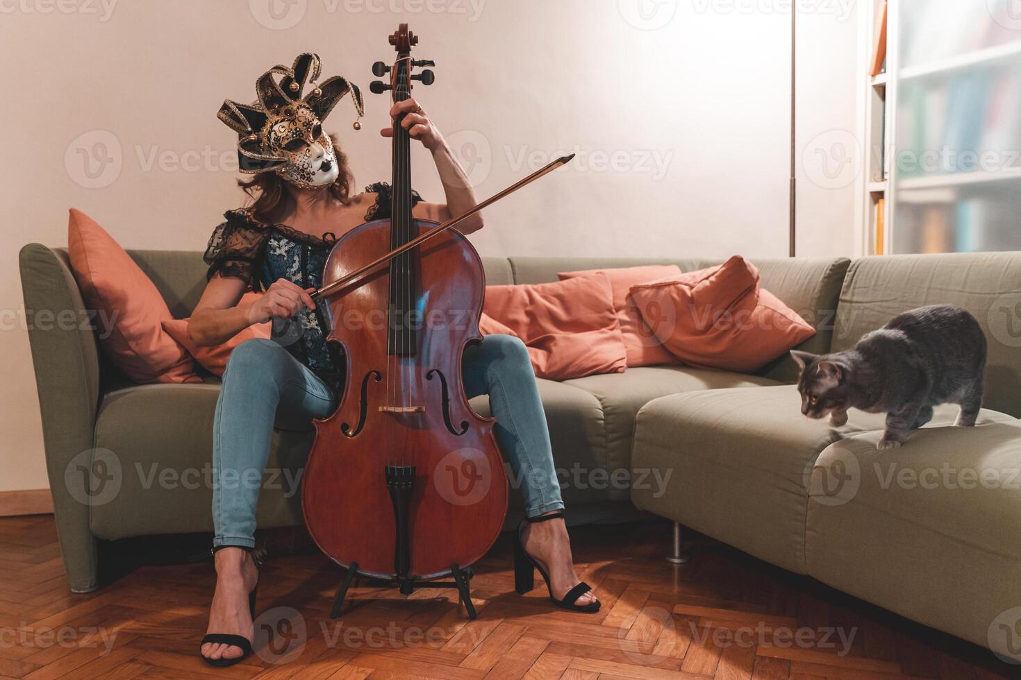 attraente donna indossare un' maschera è giocando un' violoncello foto