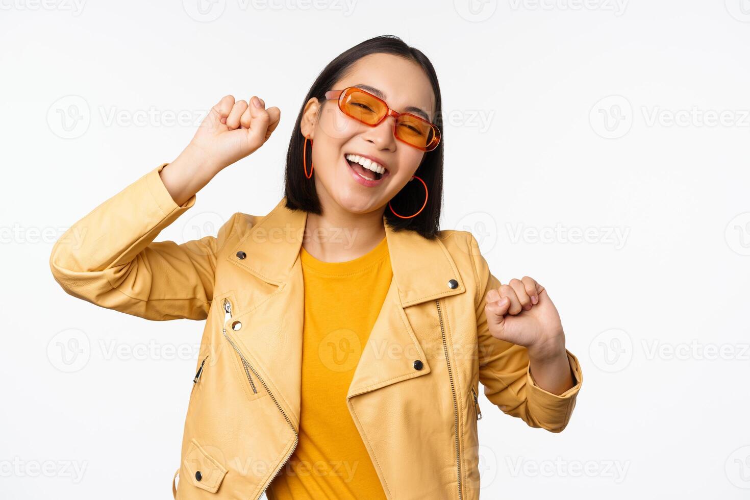 contento elegante coreano ragazza nel occhiali da sole, danza e ridendo, sorridente spensierato, in piedi al di sopra di bianca sfondo foto