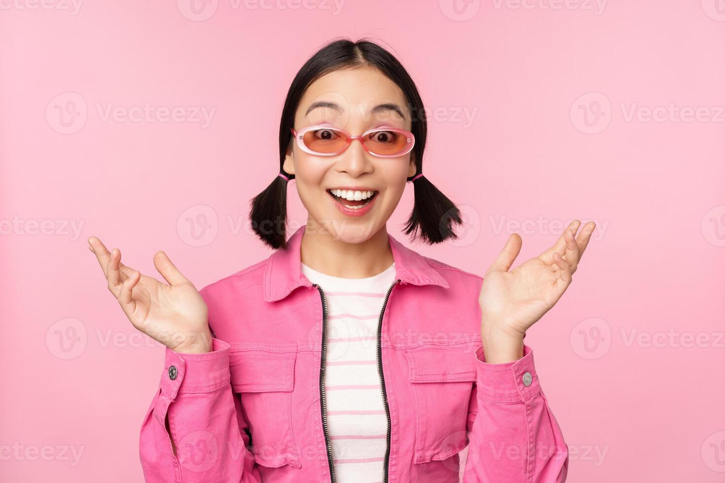 Immagine di asiatico ragazza guardare sorpreso e emozionato, sorridente, stupito reazione per grande notizia, in piedi al di sopra di rosa sfondo foto