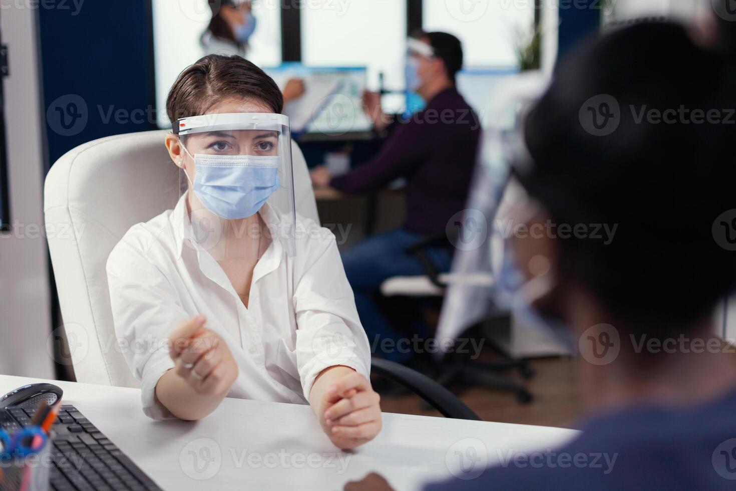 africano dipendente discutere con manager a posto di lavoro indossare viso maschera per covid19. multietnico squadra Lavorando nel azienda con nuovo normale rispetto sociale distanza perché di globale pandemia con coronavirus. foto