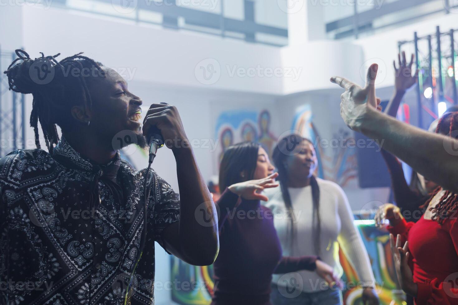 sorridente allegro africano americano uomo cantando nel microfono mentre discoteca con gli amici. giovane spensierato clubber festa, Tenere mic e godendo karaoke nel affollato discoteca foto