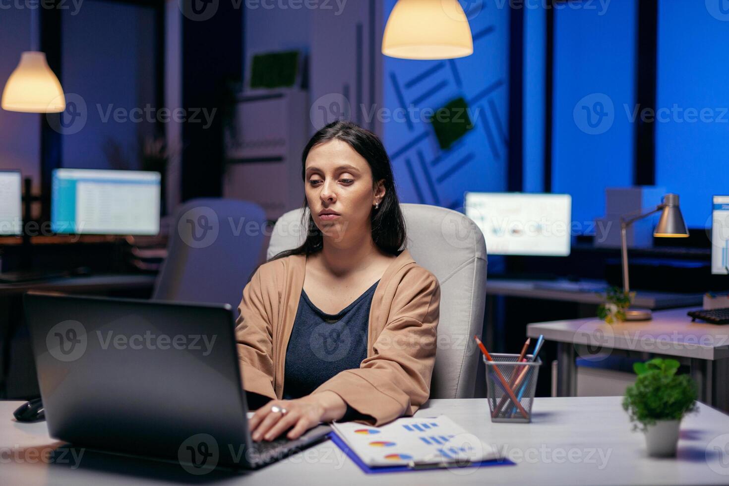 focalizzata imprenditore signora Lavorando su sua il computer portatile fare lavorare troppo per finire un' Scadenza. inteligente donna seduta a sua posto di lavoro nel il corso di in ritardo notte ore fare sua lavoro. foto