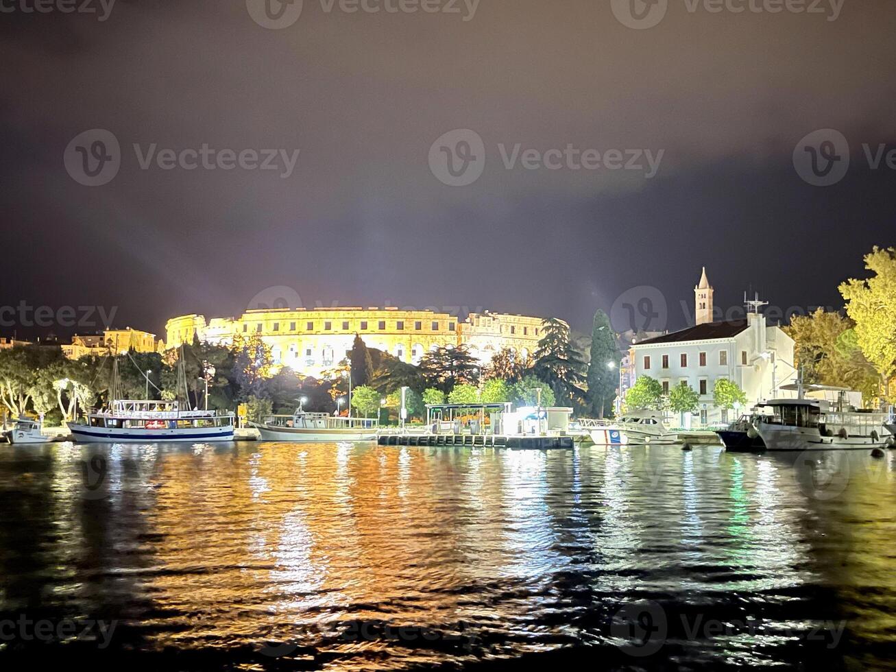 un' città a notte con Barche su il acqua foto