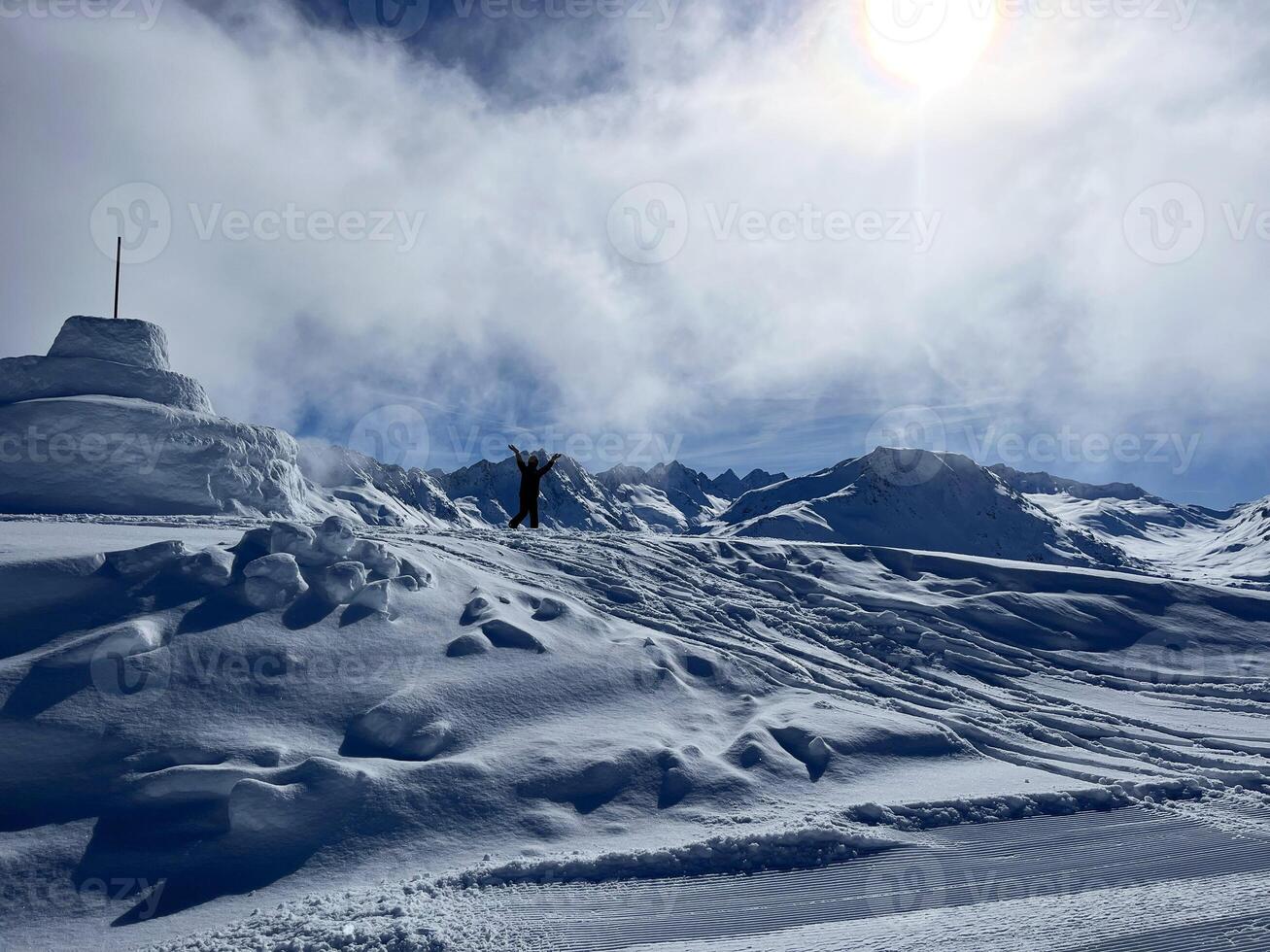 un' silhouette di uomo in piedi su superiore di un' neve coperto montagna foto