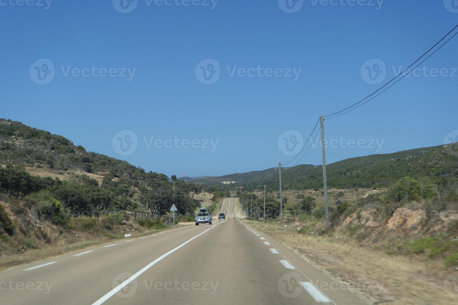 un' auto guida giù un' strada con un' collina nel il sfondo foto