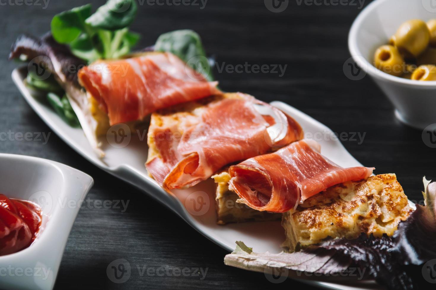 Deliziosa frittata spagnola di patate con prosciutto serrano e olive foto