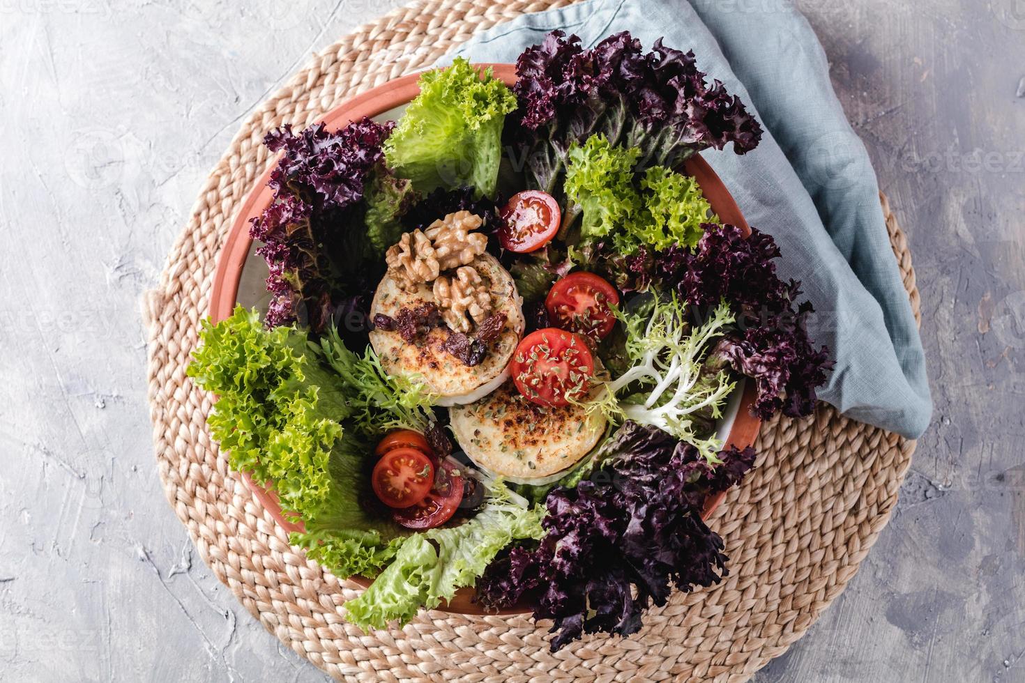 insalata con lattuga, pomodorini, formaggio di capra, noci e spezie foto