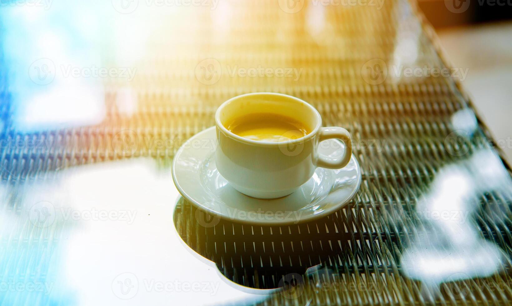 un' tazza di caffè nel il mattina nel il sole su un' bicchiere tavolo foto
