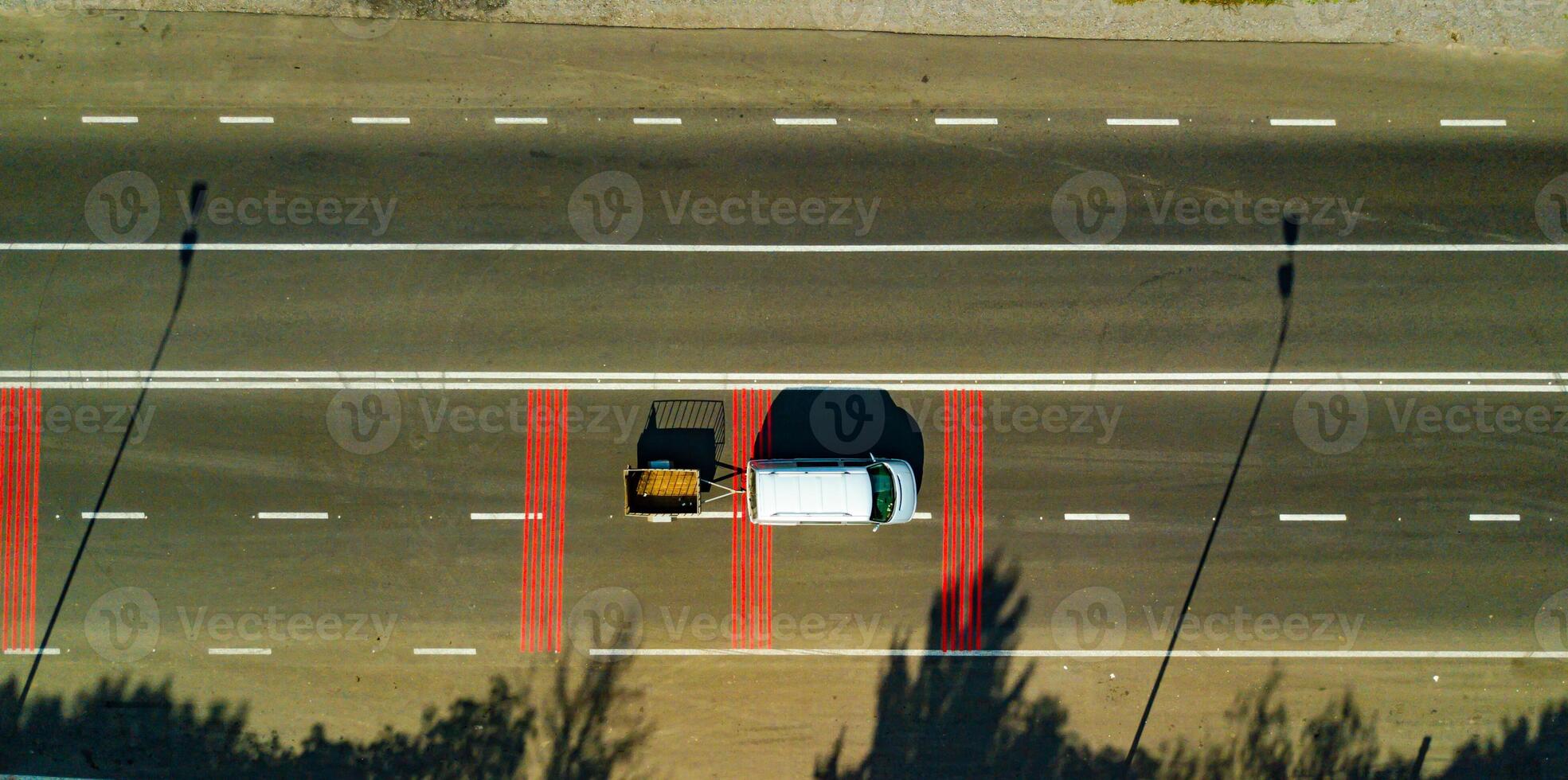 un' auto con un' trailer unità lungo un' autostrada con rosso segnato Linee. aereo Visualizza foto