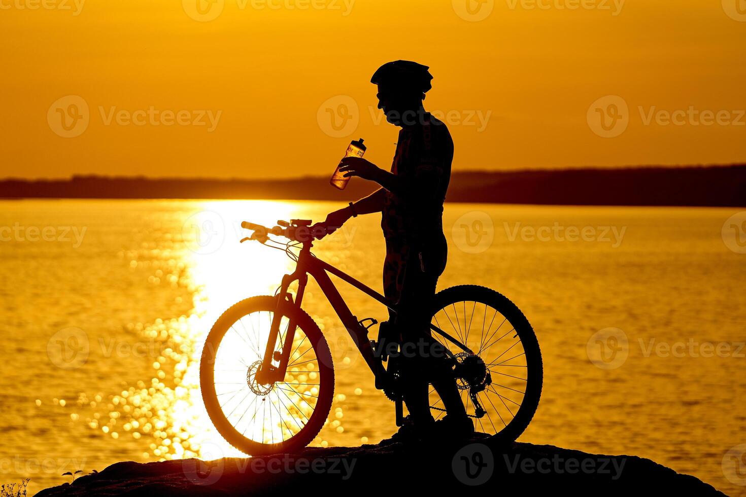 silhouette di un' ciclista con tramonto sfondo. arancia cielo, passatempo, salutare abitudini. potabile acqua mentre riposo foto