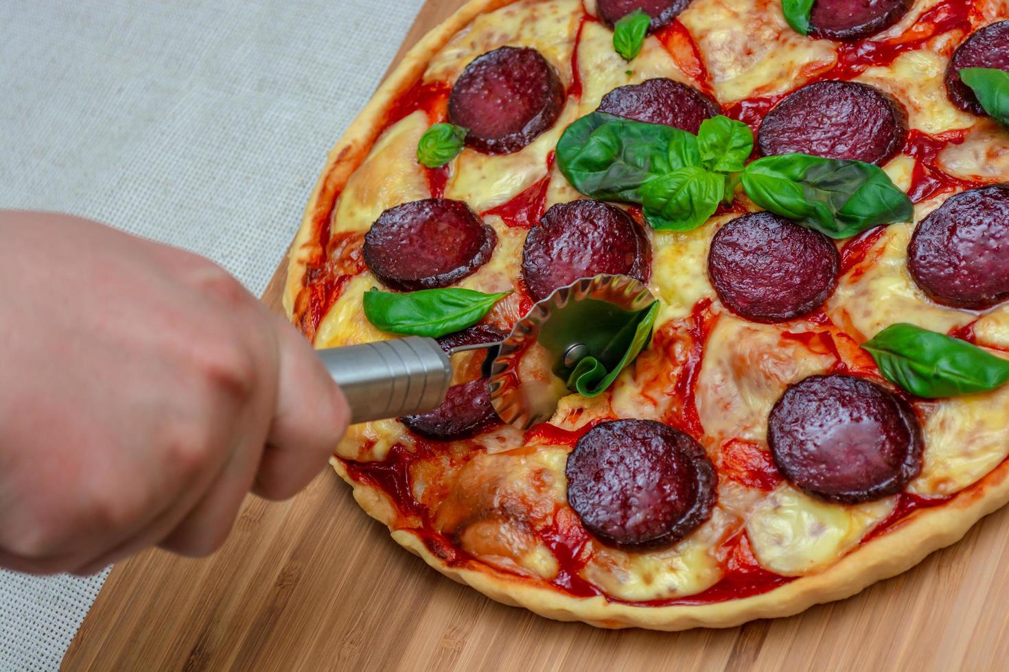 tagliare la pizza fatta in casa su un tagliere da cucina foto