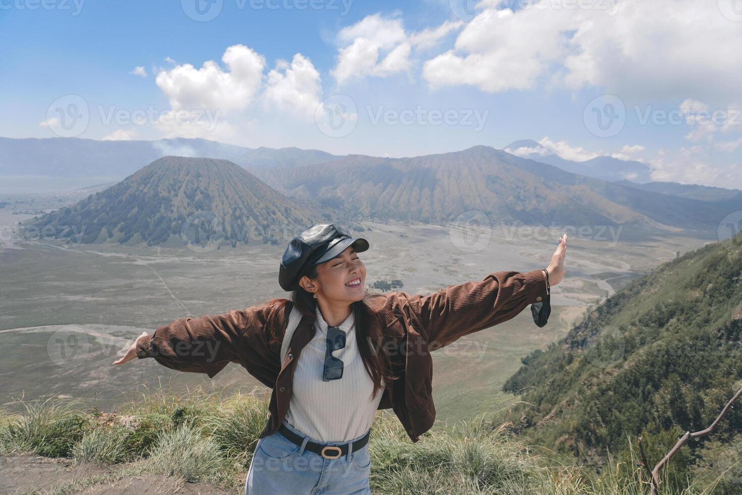 un asiatico ragazza in piedi su un' collina traccia nel bromo, godendo Visualizza di bromo, un' meraviglioso scenario nel drammatico collina foto