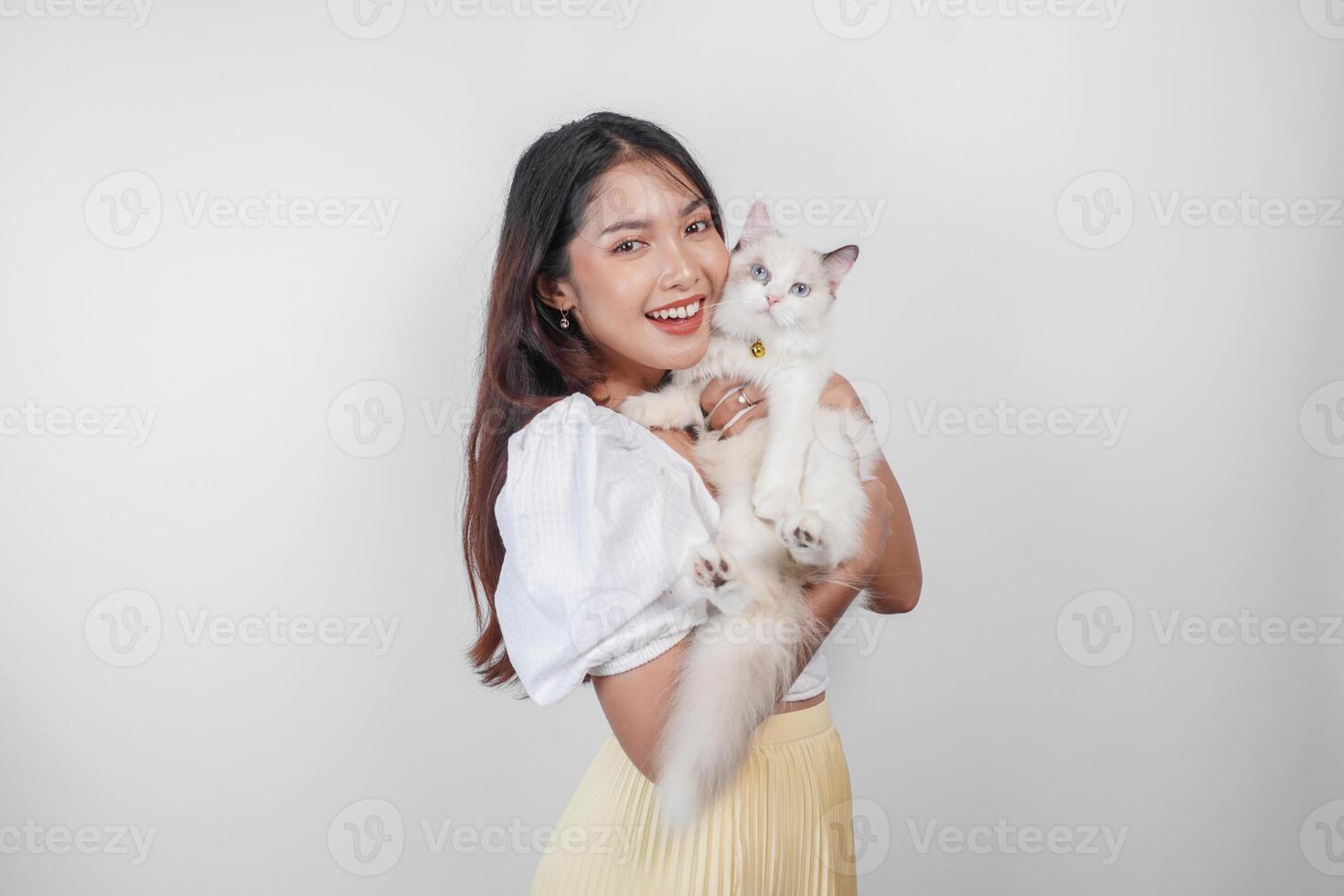 ritratto di giovane asiatico donna Tenere carino bambola di pezza gatto con blu occhi. femmina abbracciare sua carino lungo capelli gattino isolato di bianca sfondo. adorabile domestico animale domestico concetto. foto