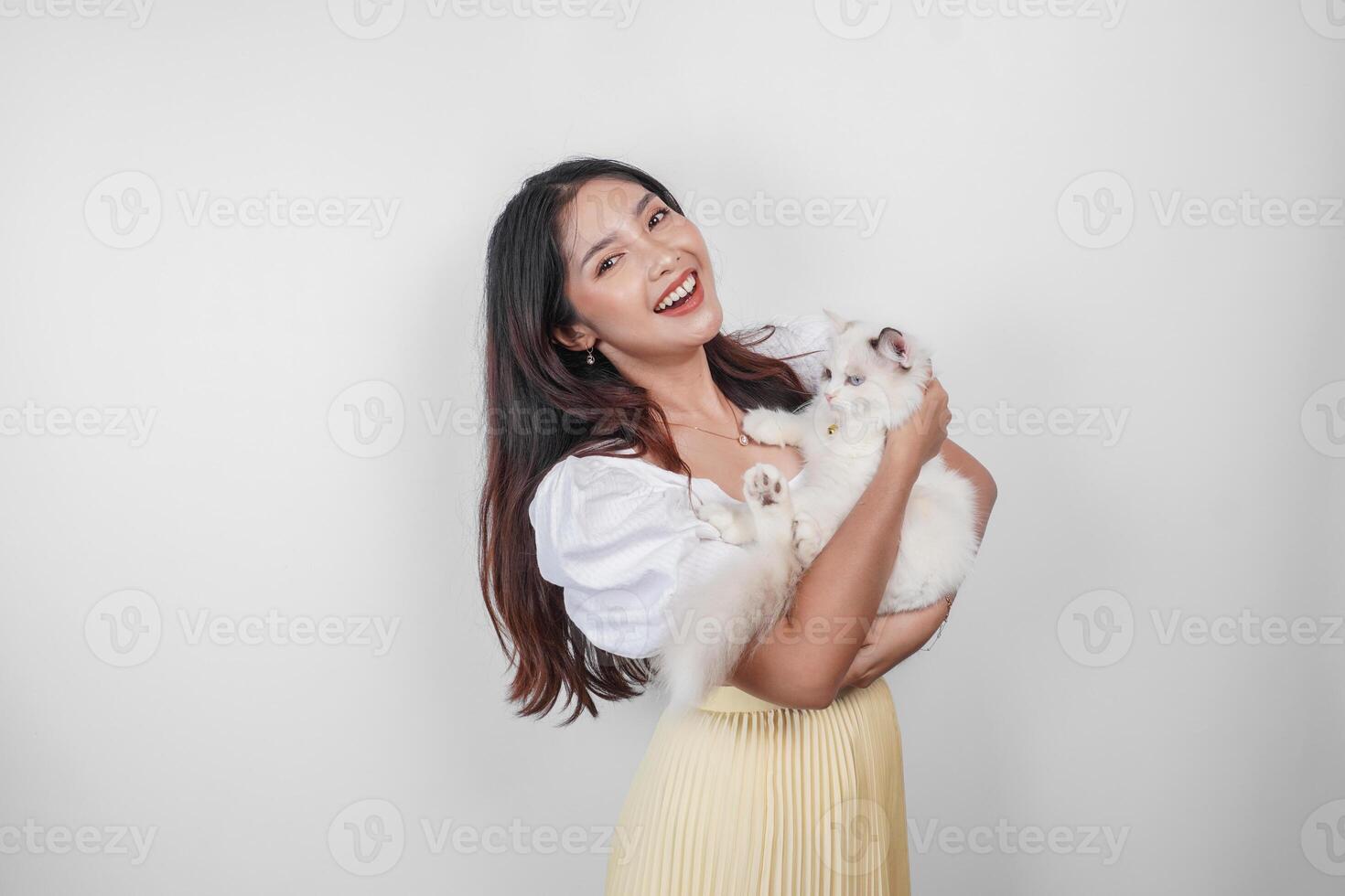 ritratto di giovane asiatico donna Tenere carino bambola di pezza gatto con blu occhi. femmina abbracciare sua carino lungo capelli gattino isolato di bianca sfondo. adorabile domestico animale domestico concetto. foto