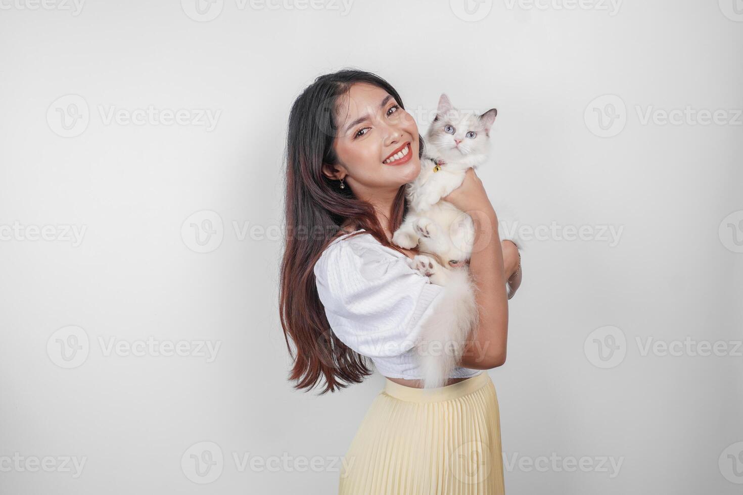 ritratto di giovane asiatico donna Tenere carino bambola di pezza gatto con blu occhi. femmina abbracciare sua carino lungo capelli gattino isolato di bianca sfondo. adorabile domestico animale domestico concetto. foto