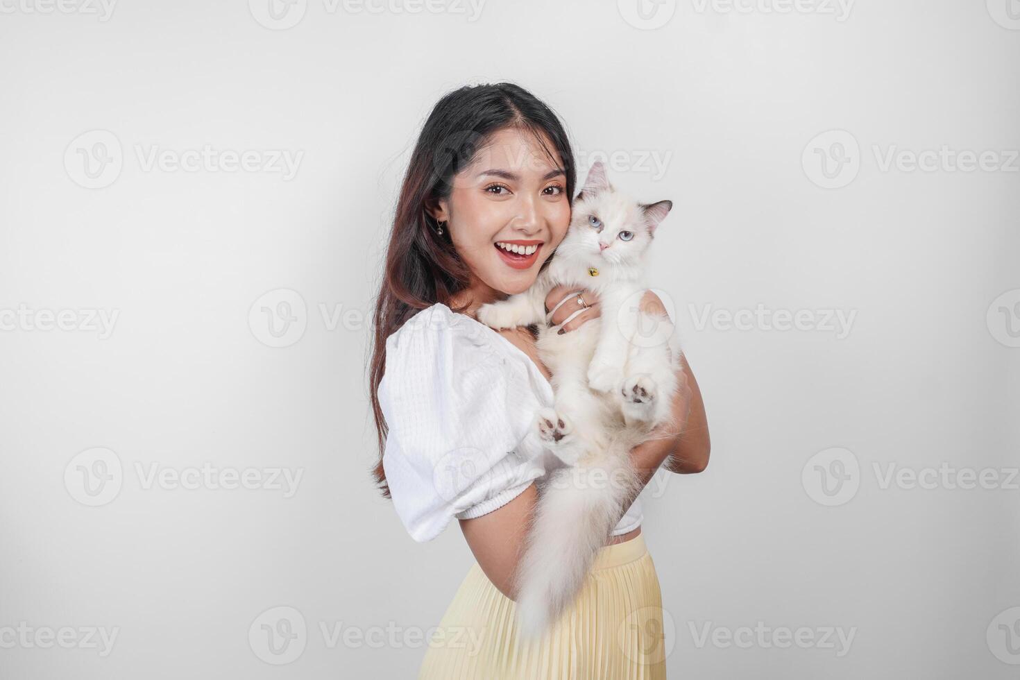 ritratto di giovane asiatico donna Tenere carino bambola di pezza gatto con blu occhi. femmina abbracciare sua carino lungo capelli gattino isolato di bianca sfondo. adorabile domestico animale domestico concetto. foto