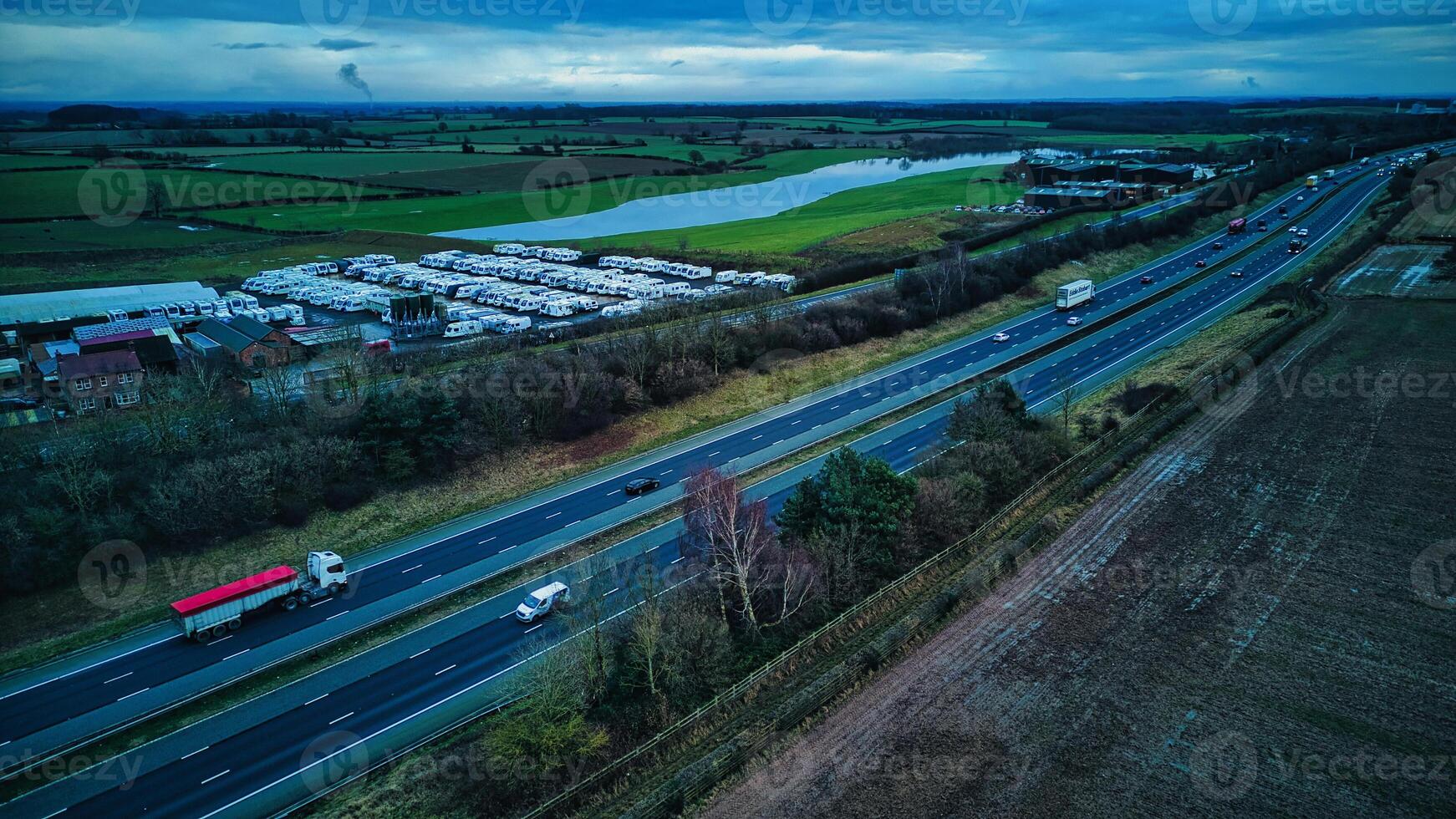 aereo Visualizza di un' autostrada con veicoli a crepuscolo, in mostra mezzi di trasporto e infrastruttura con un' rurale sfondo. foto