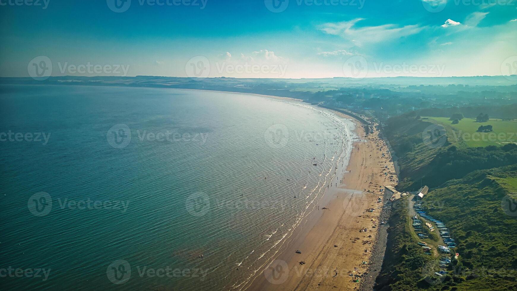 aereo Visualizza di un' radicale costa con un' sabbioso spiaggia, calma mare, e verdura sotto un' blu cielo con sparpagliato nuvole nel filey, Inghilterra. foto