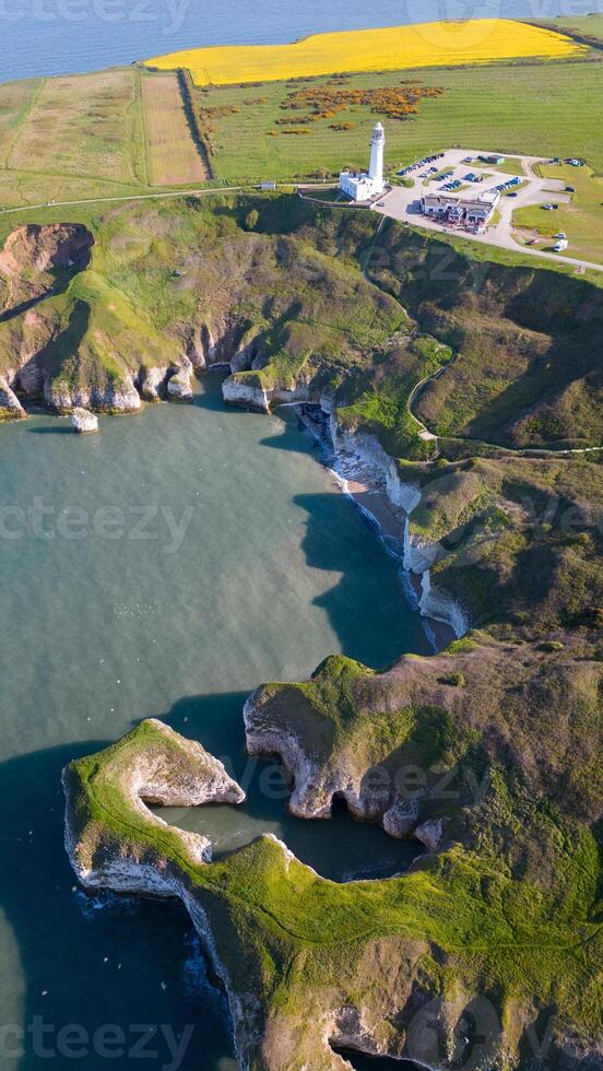 aereo Visualizza di un' aspro costa con un' faro, blu mare, e verde i campi sotto un' chiaro cielo nel Flamborough, Inghilterra foto