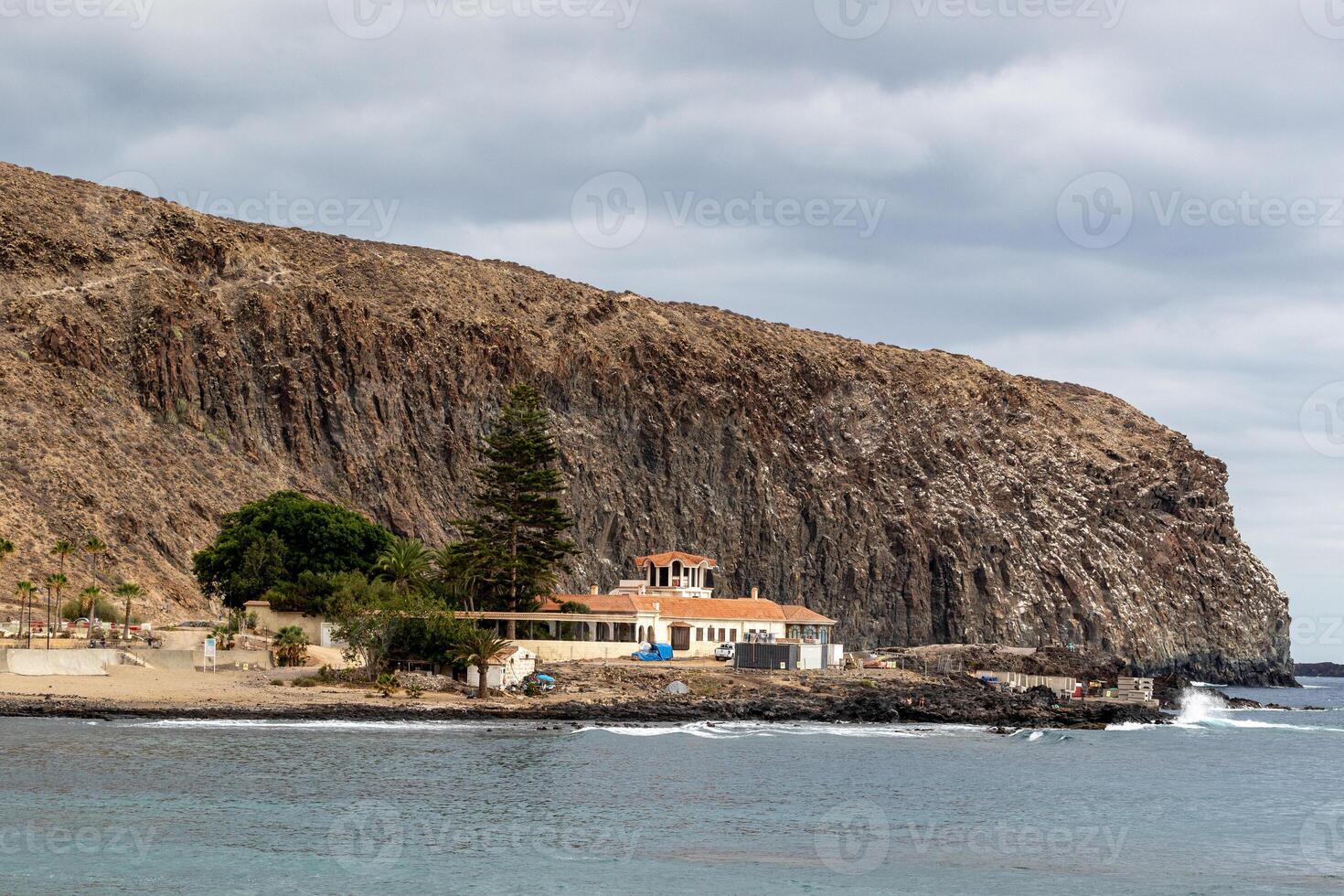 appartato Casa di il mare con un' montagna fondale sotto nuvoloso cieli nel los cristiano, tenerife. foto