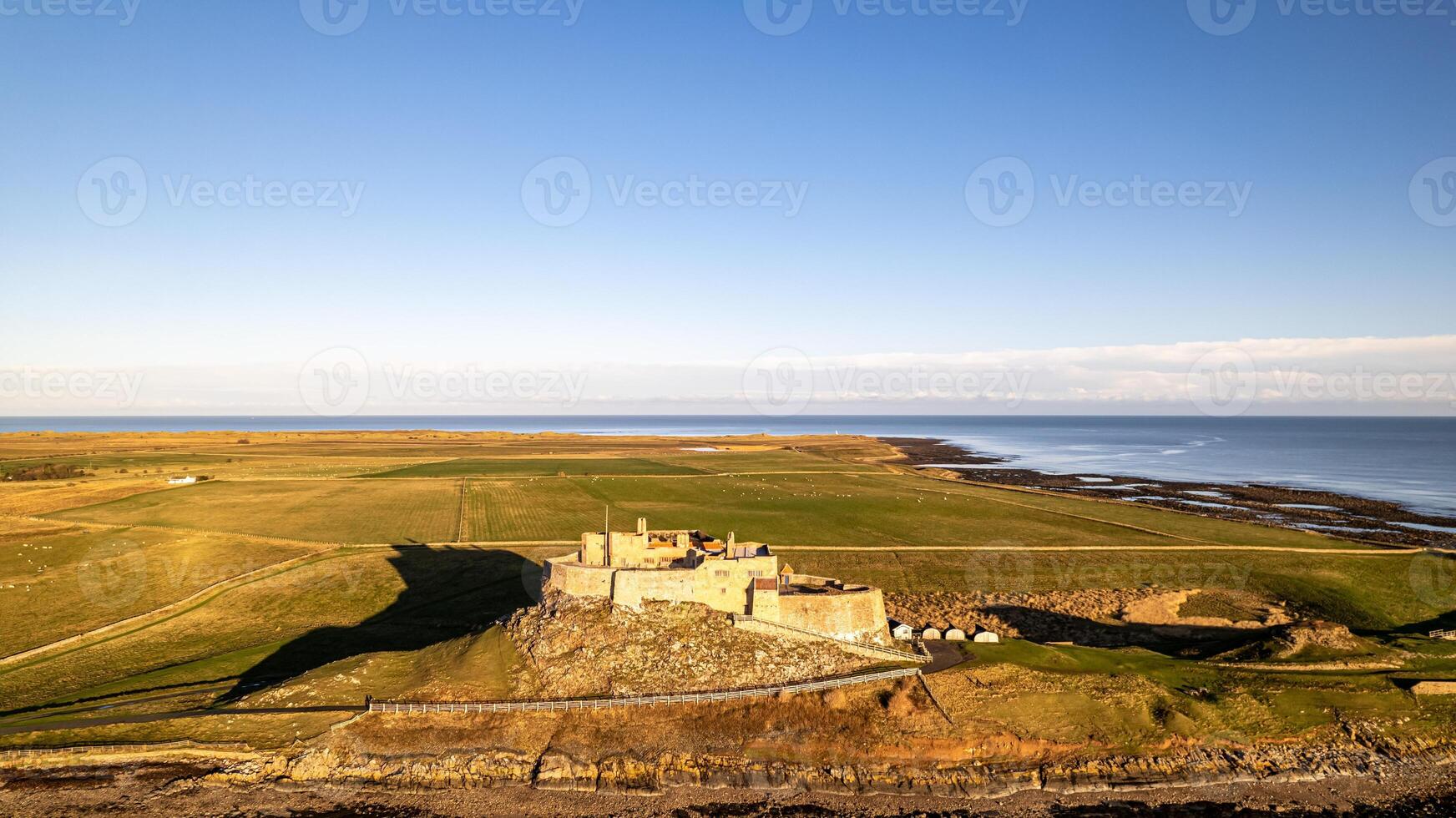 aereo Visualizza di un' costiero castello con circostante i campi sotto un' chiaro blu cielo. foto