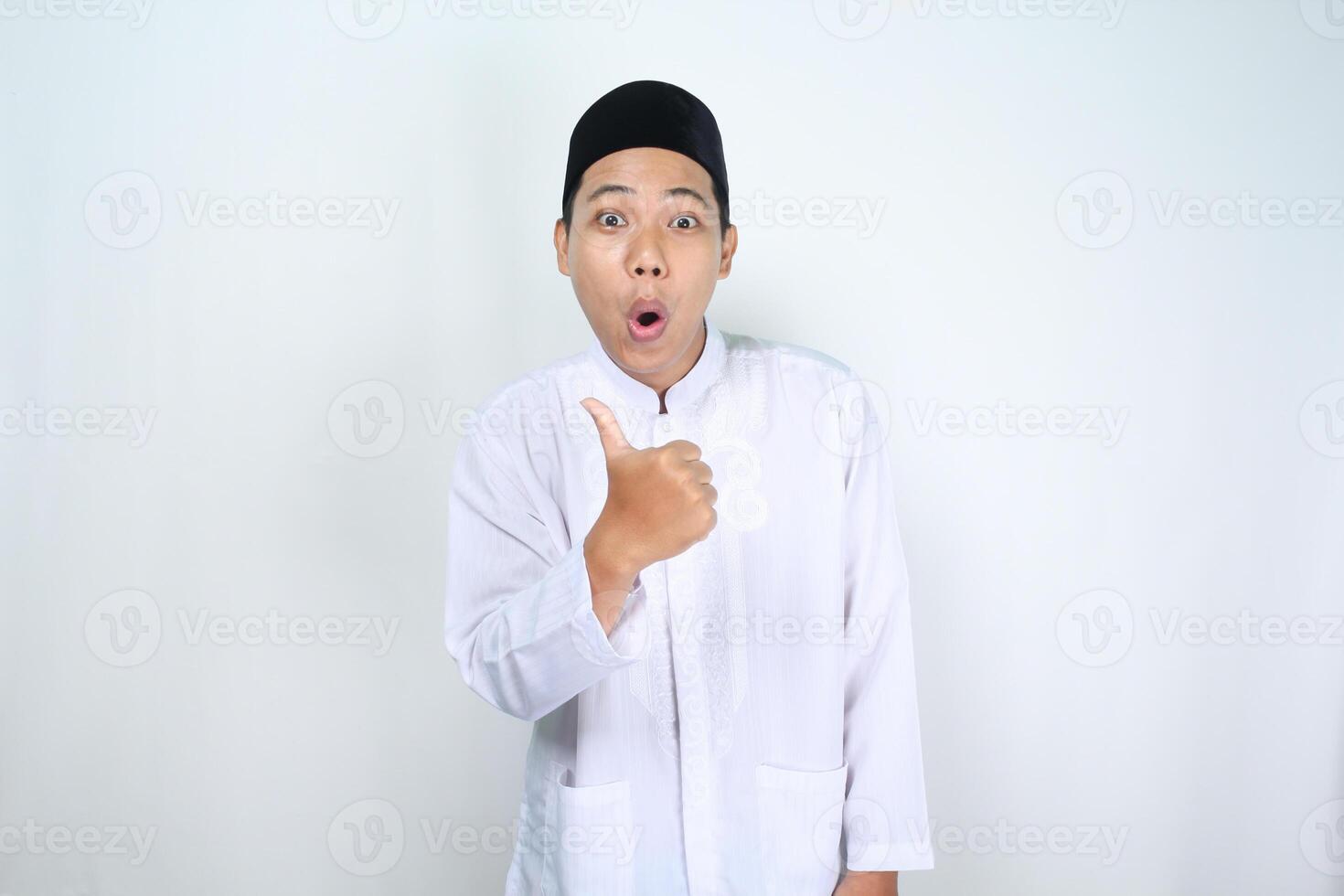scioccato asiatico uomo musulmano mostrare pollici su isolato su bianca sfondo foto
