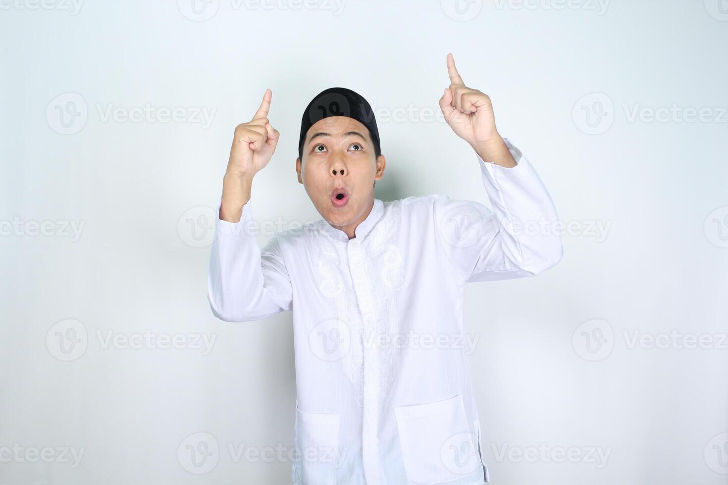 scioccato asiatico musulmano uomo puntamento per sopra isolato su bianca sfondo foto