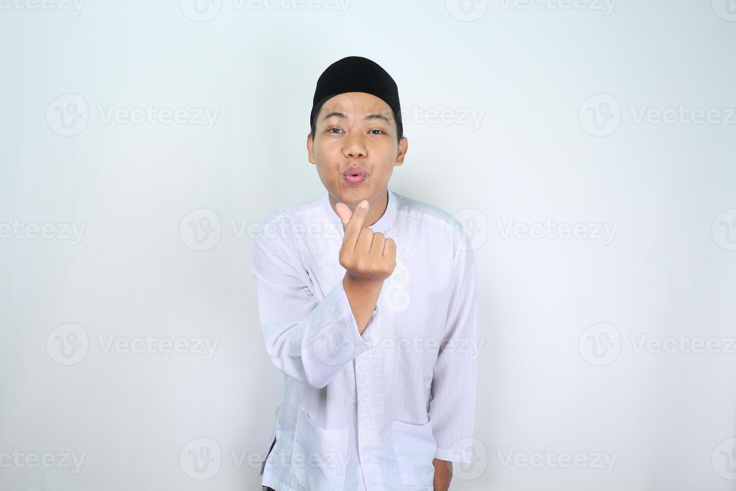 contento asiatico uomo musulmano soffiaggio bacio con dito sagomato coreano amore cartello per telecamera isolato su bianca sfondo foto