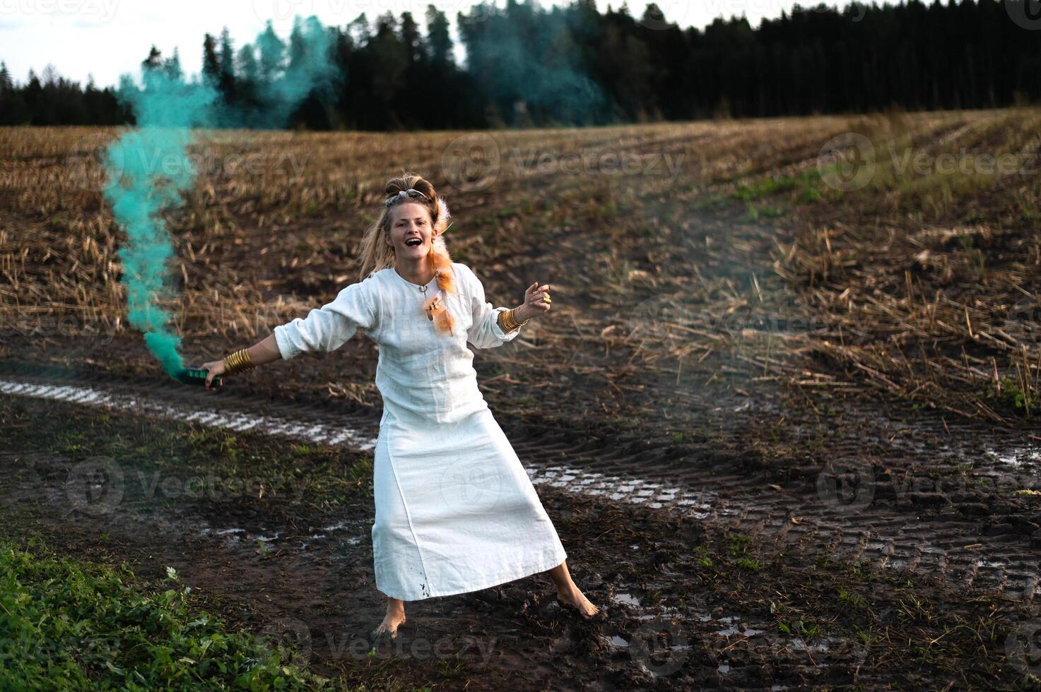 allegro giovane donna con canne balli nel colorato Fumo nel un' campo foto