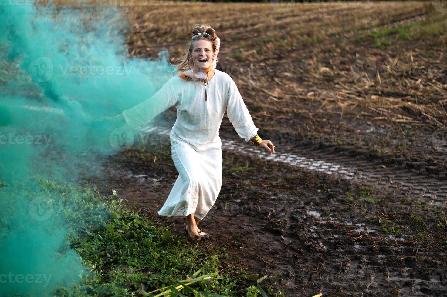 allegro giovane donna con canne balli nel colorato Fumo nel un' campo foto