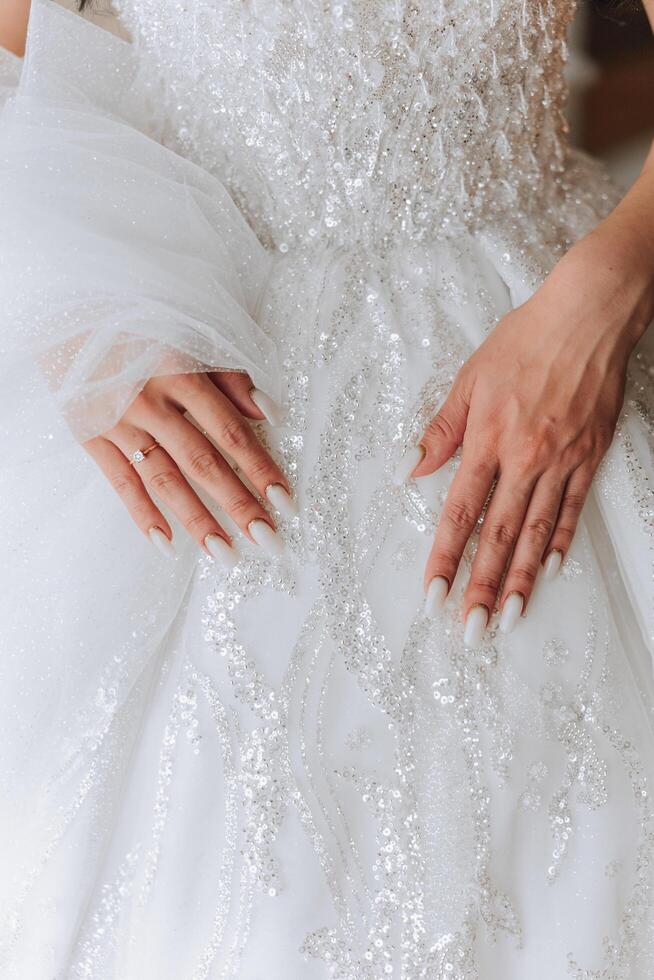 avvicinamento di femmina mani toccante vestire. Da donna manicure. un' lussuoso nozze squillare su un' donna di dito. foto