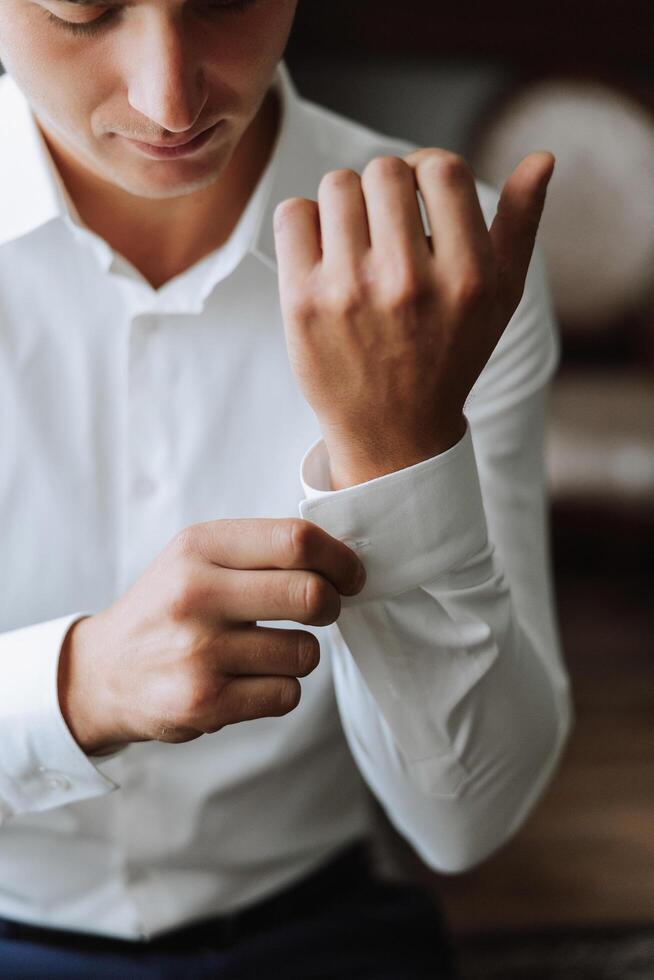 attività commerciale camicia. un' uomo nel un' bianca camicia si allaccia il pulsanti. giovane politico, maschio stile, uomo d'affari abbottonatura camicia, maschio mani avvicinamento, americano, europeo uomo d'affari foto