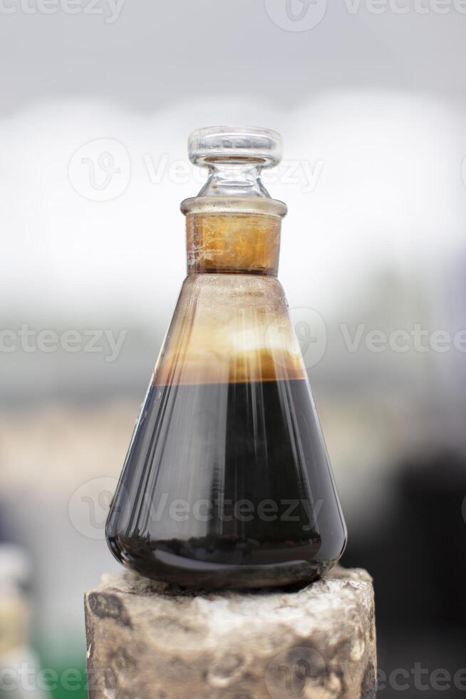 nero di spessore liquido nel un' bicchiere borraccia su un' grigio sfondo. foto