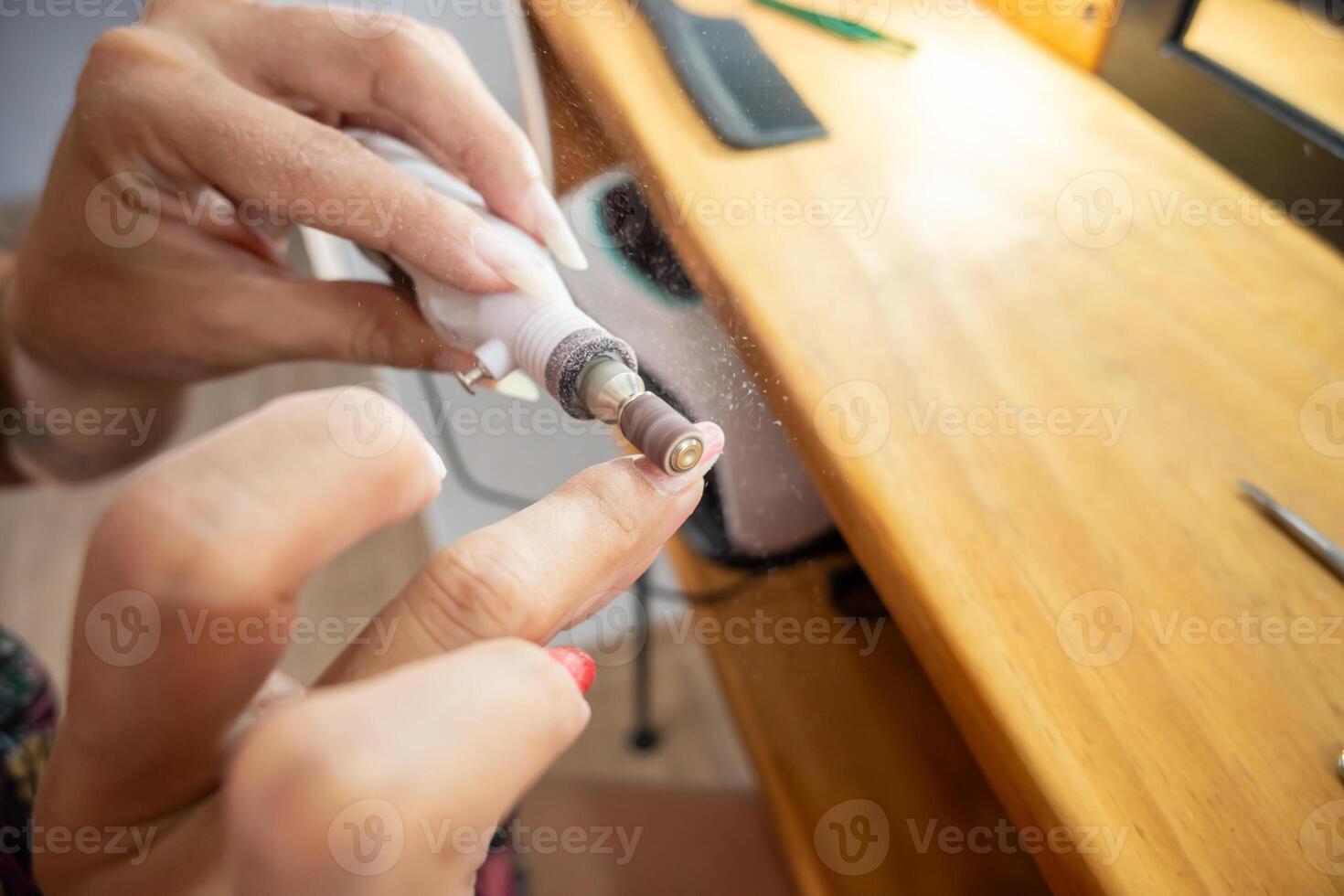 vicino su foto di un' donna rimozione il semipermanente chiodo polacco a partire dal sua Chiodi con il carta vetrata ruota.