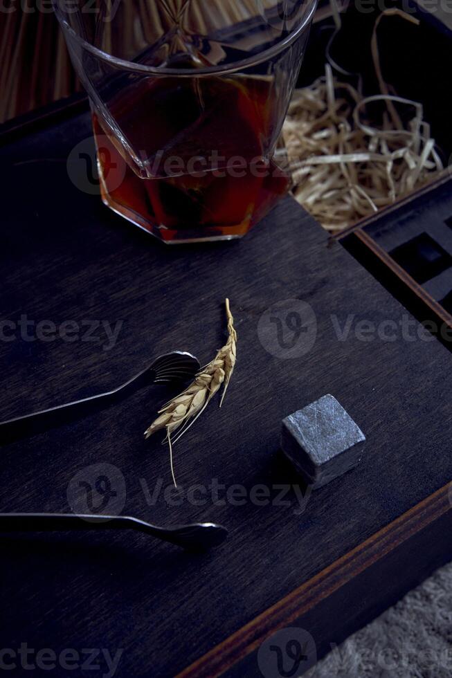 whisky con pinza, pietra cubi, di legno scatola e Grano su tappeto foto