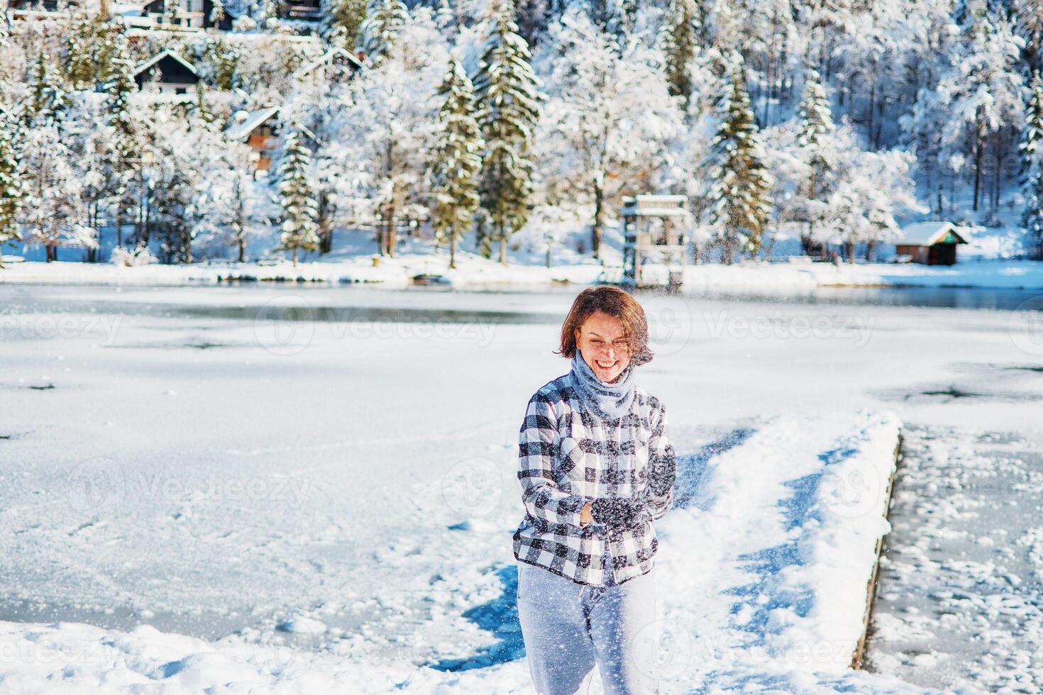 ragazza giocare con neve di il lago nel davanti di montagne foto