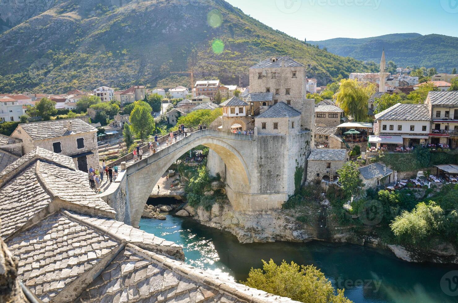 Visualizza di il vecchio ponte nel mostar città nel bosnia e erzegovina durante un' soleggiato giorno. neretva fiume. unesco mondo eredità luogo. persone a piedi al di sopra di il ponte. foto