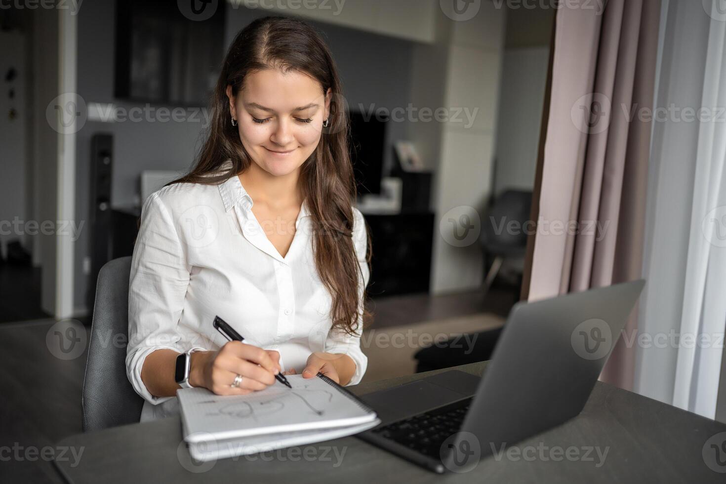 giovane donna utilizzando il computer portatile nel casa posto di lavoro, scrittura Appunti, femmina alunno apprendimento e Guardando in linea seminario web o ascoltando Audio corso, e-learning formazione scolastica concetto. foto