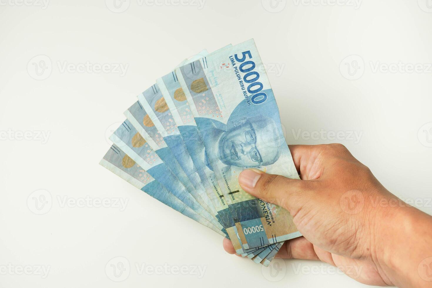 maschio mano Tenere un' lotto di indonesiano i soldi rupia su un' isolato bianca sfondo. attività commerciale concetto ,finanziario concetto foto