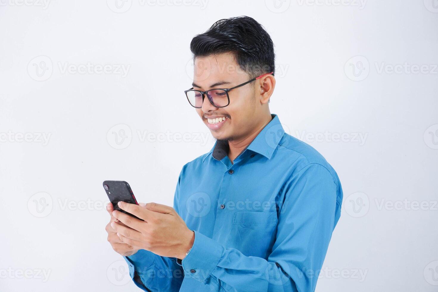 bello sorridente o contento asiatico giovane dipendente uomo con bicchieri Tenere inteligente Telefono chat su bianca isolato sfondo. foto