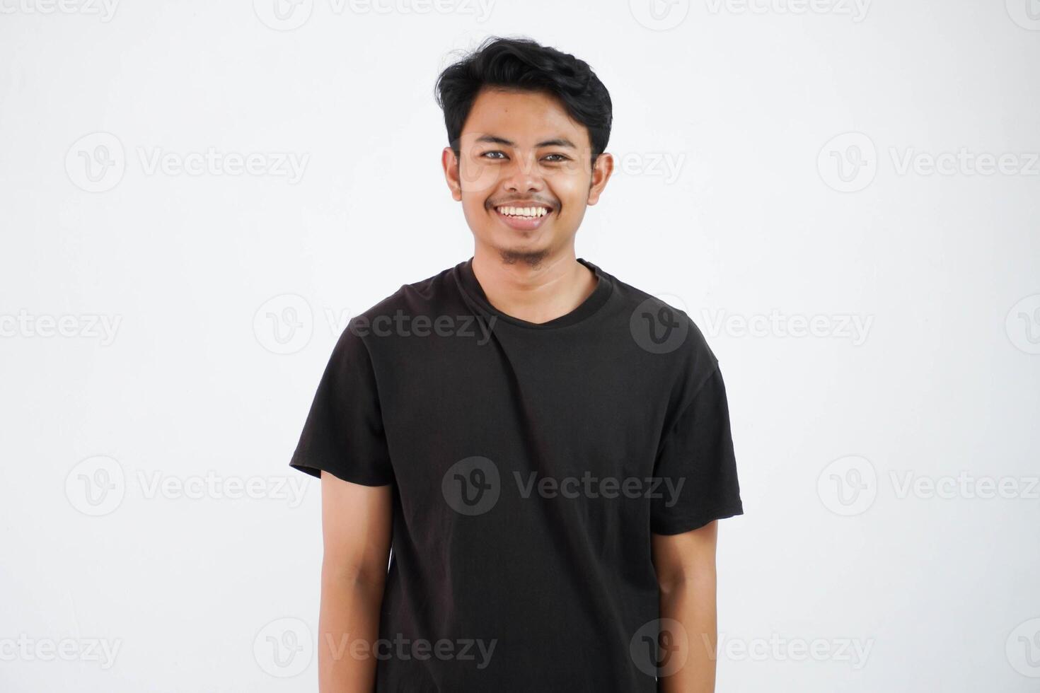 sorridente giovane asiatico uomo in piedi guardare telecamera indossare nero t camicia isolato su bianca sfondo foto