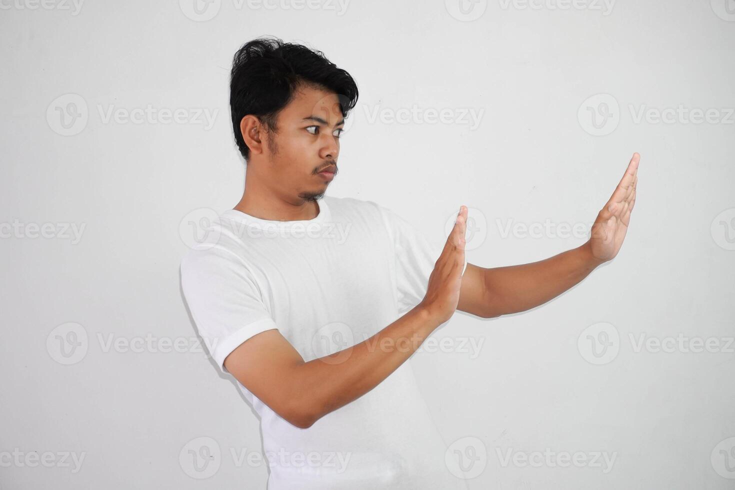 scontento bello giovane asiatico uomo indossare bianca t camicia mostrando fermare cartello isolato su bianca sfondo foto